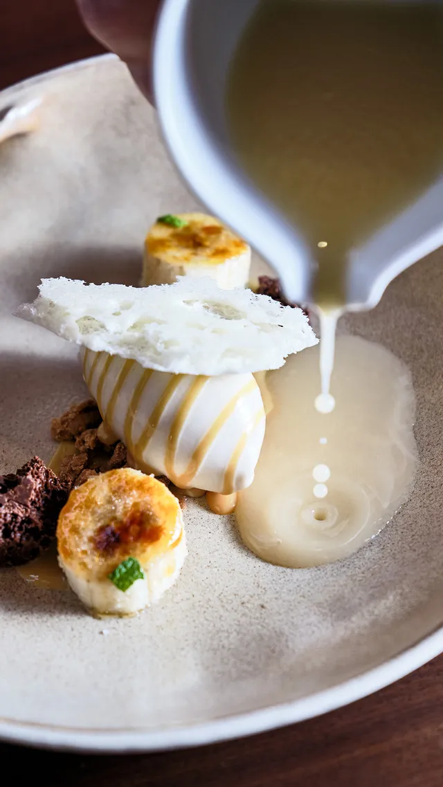 Gourmet-Dessert mit Sauce über Eis, Kuchenstücken und Schokolade auf Keramikteller